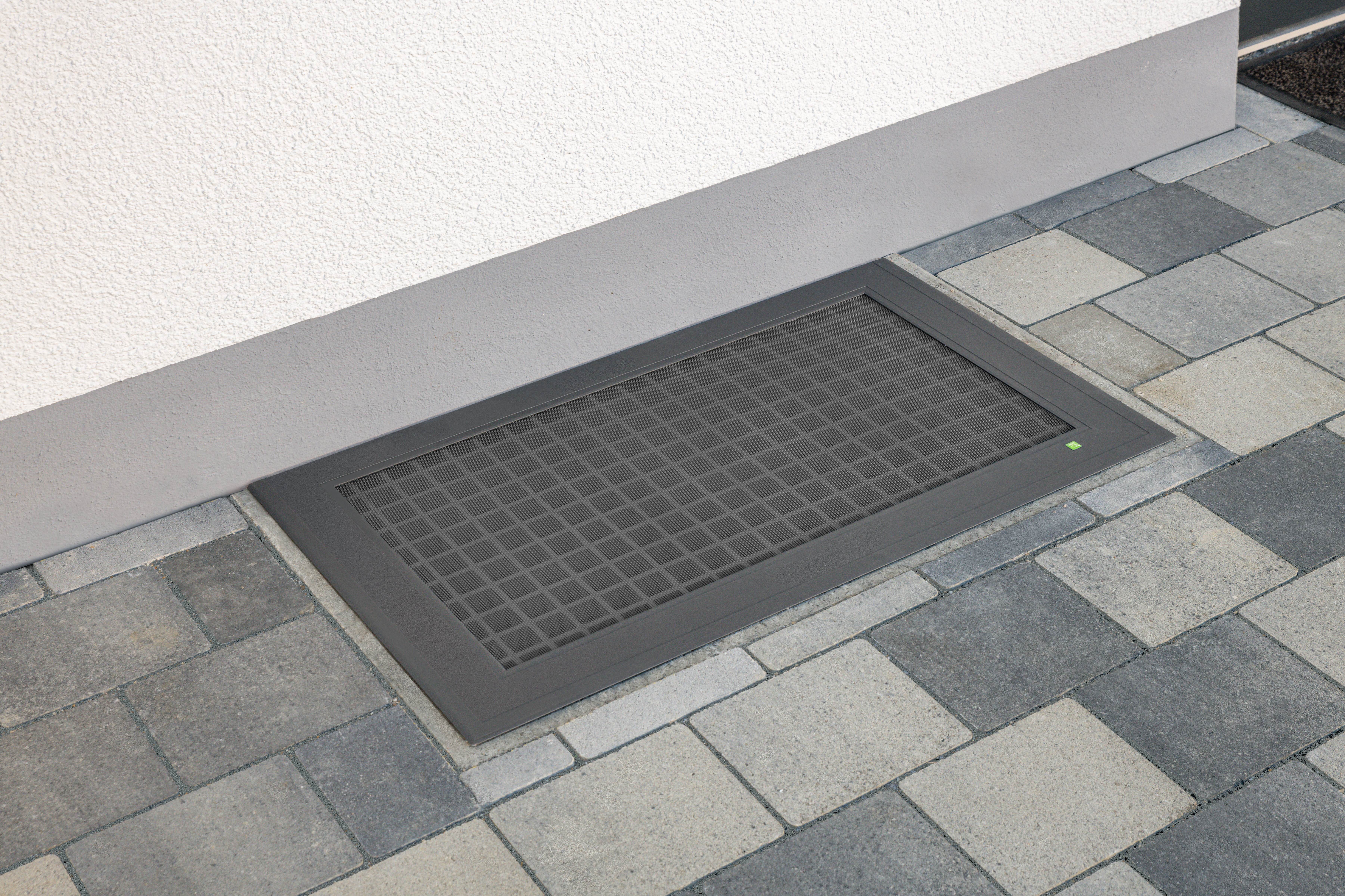Begehbare Kellerschachtabdeckung aus Aluminium mit integriertem Schutzgitter vor einem Hauseingang